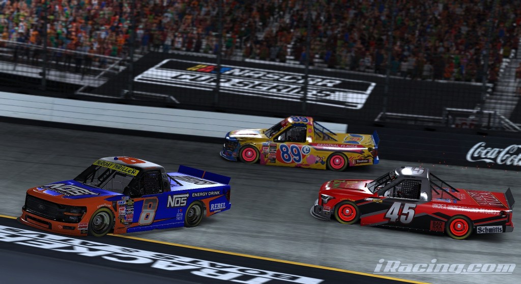 Three race trucks competing close to each other on a track during a NASCAR event, with spectators visible in the background.