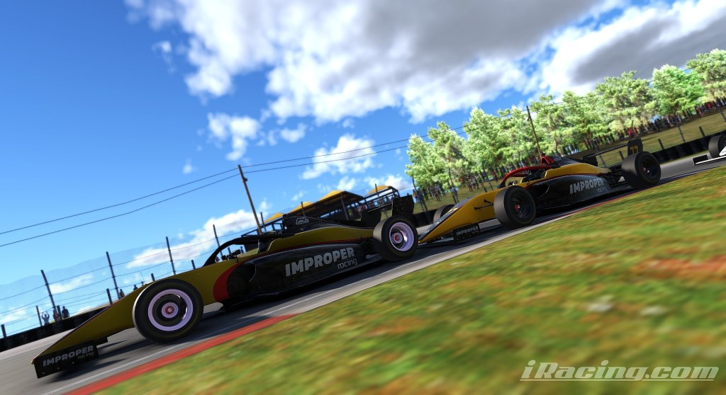 Two race cars from Team Improper competing closely on the Mid-Ohio Sports Car Course, with a blue sky and trees in the background.