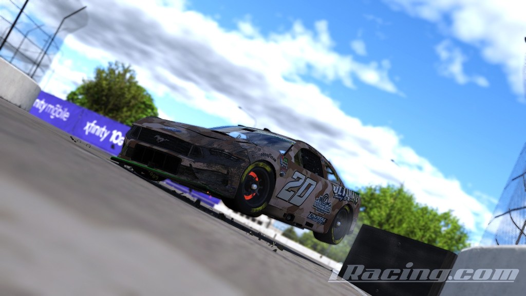 A racing car with the number 20 is shown airborne after hitting a wall during a race, with a blurred background depicting a race track and blue skies.