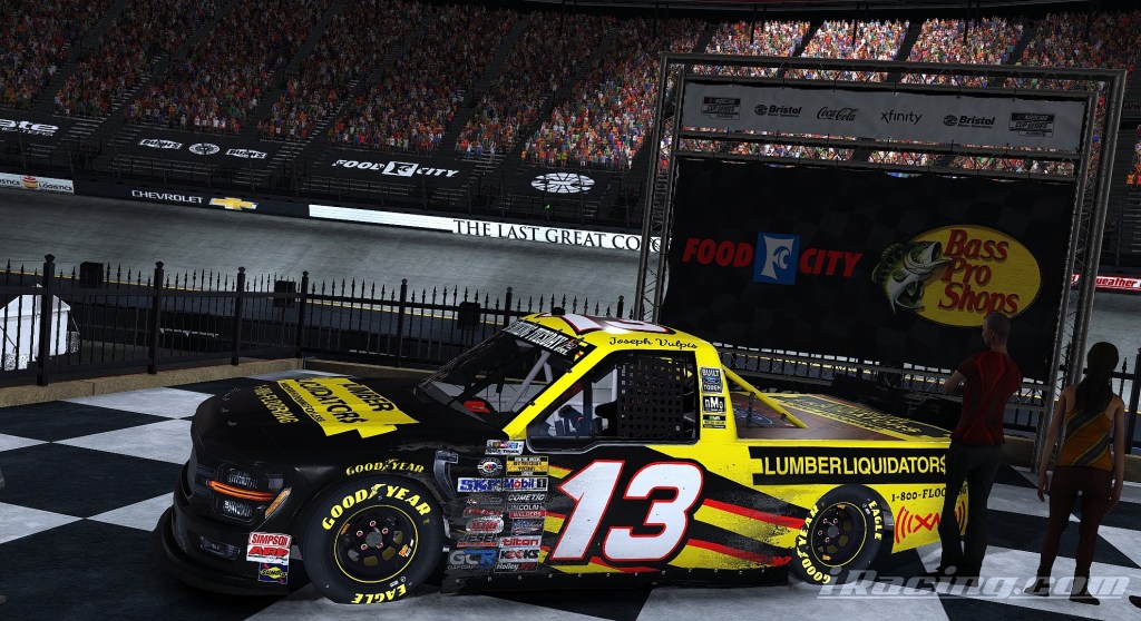 Joseph Vulpis celebrating in his #13 truck on the victory lane at Bristol, with a cheering crowd in the background.