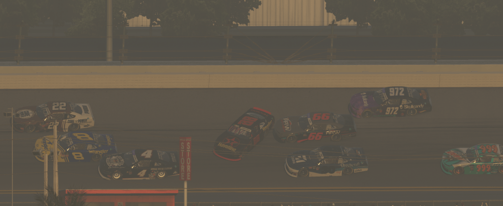 A group of race cars competing closely on the track at Daytona International Speedway, with some cars experiencing a collision.