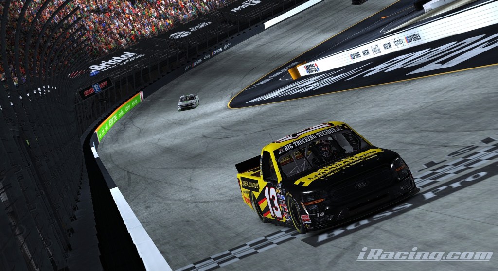 A racing scene at Bristol Motor Speedway featuring a yellow and black truck number 13 and a white truck in the background, surrounded by a packed grandstand.