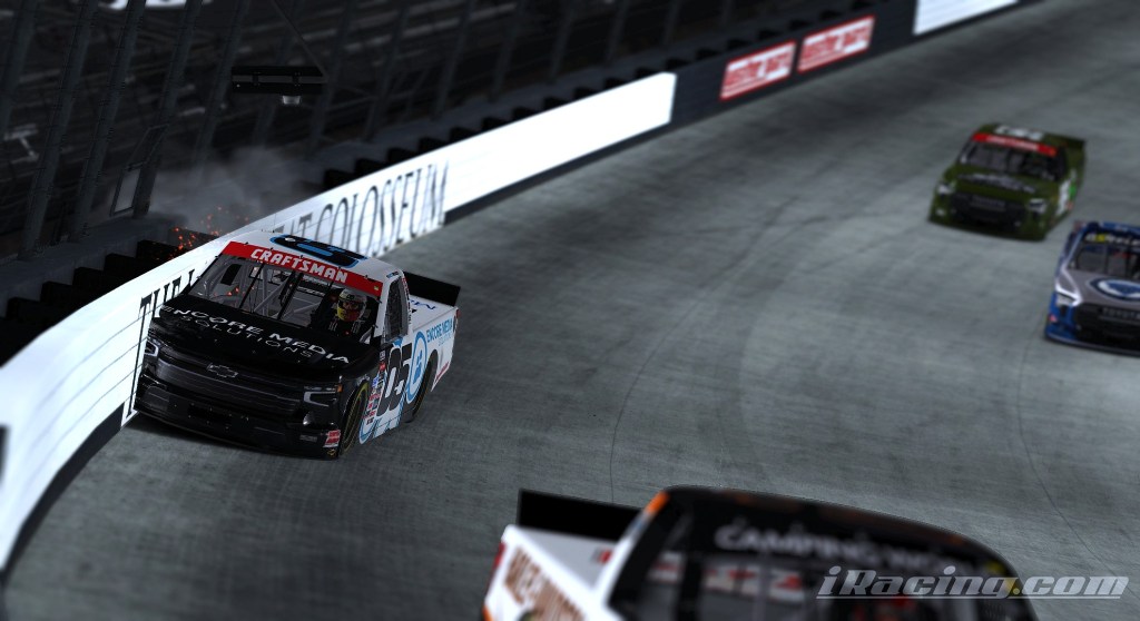 A racing scene depicting a truck crashed against the wall at Bristol Motor Speedway, with sparks flying from the impact and other trucks visible in the background.